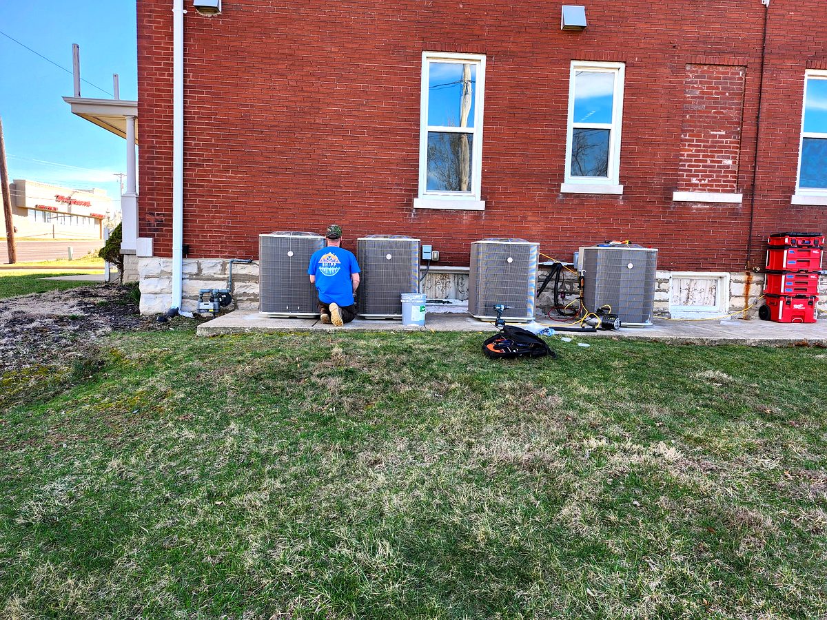 Eric servicing commercial AC units at a brick building
